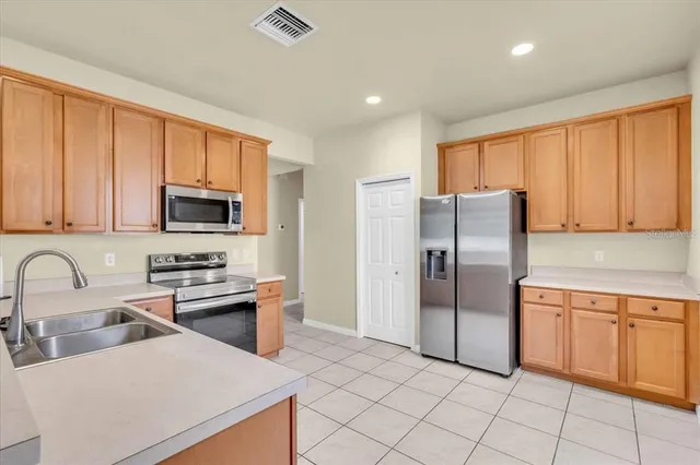 a kitchen with stainless steel appliances granite countertop a refrigerator stove top oven and sink