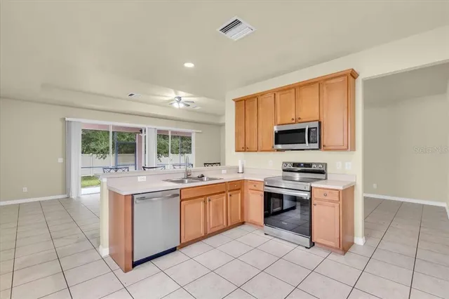 a kitchen with stainless steel appliances granite countertop a stove top oven a sink dishwasher and white cabinets next to a window