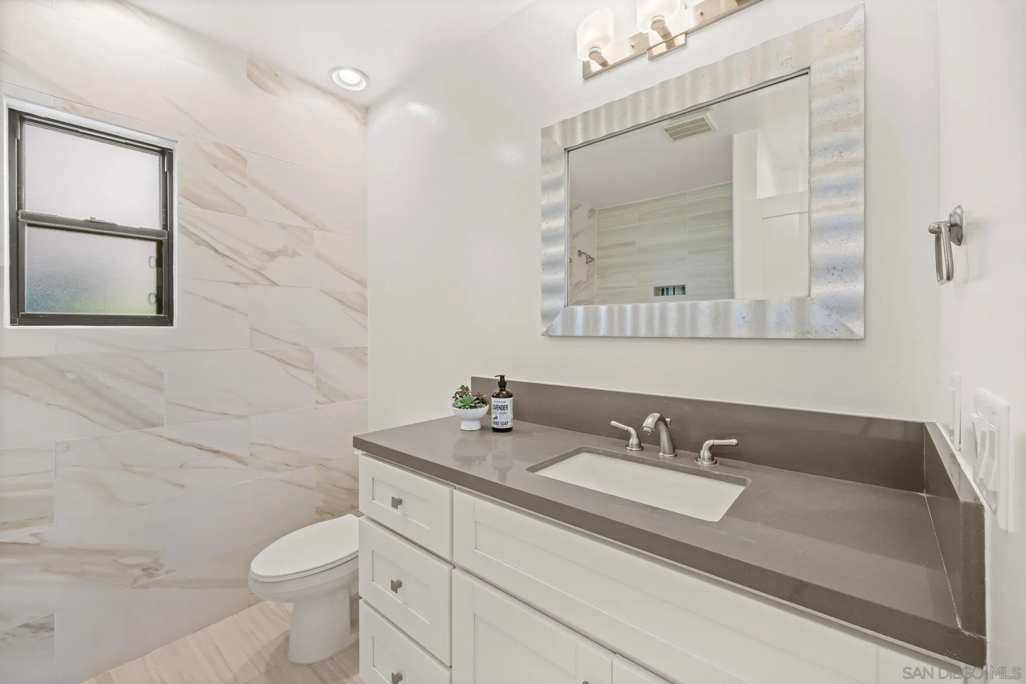 1712 Beryl Street San Diego, CA 92109 - Photo 15 of 37 a bathroom with a granite countertop sink a toilet and a mirror