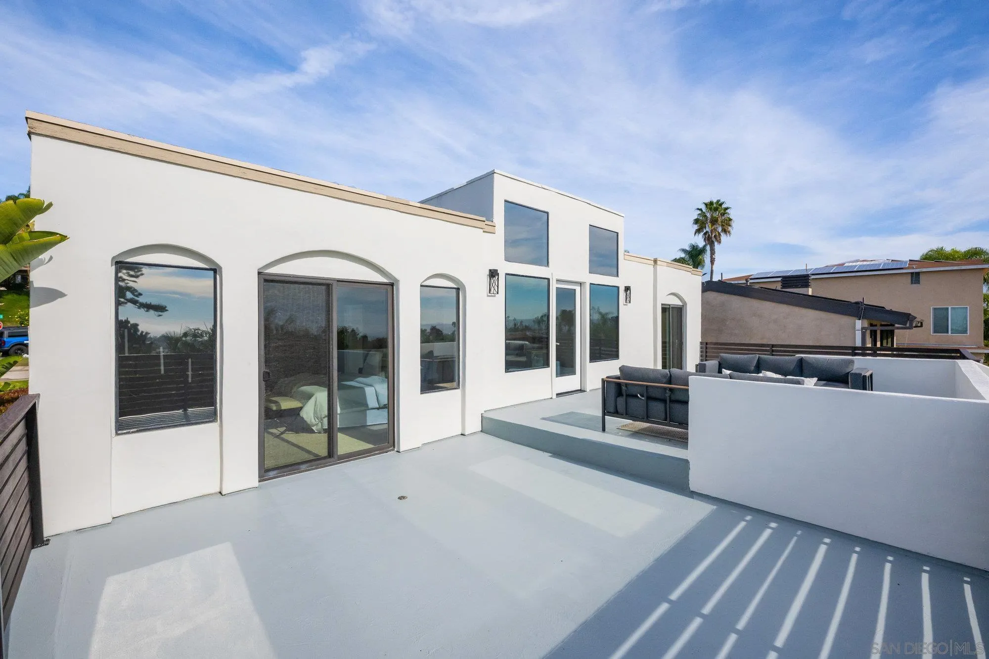 1712 Beryl Street San Diego, CA 92109 - Photo 26 of 37 a living room with furniture a flat screen tv and a floor to ceiling window