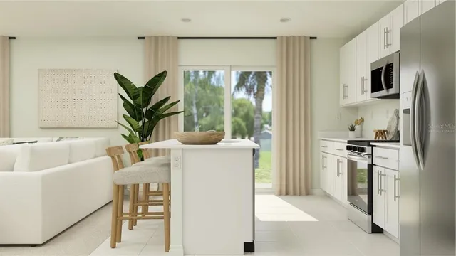 a living room with stainless steel appliances a window a sink and a refrigerator