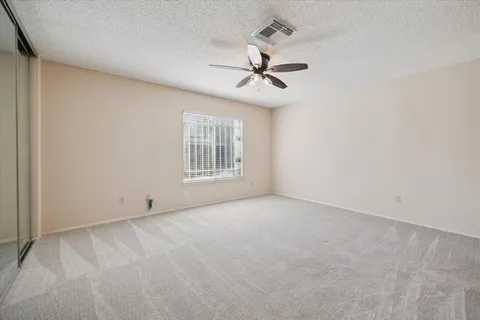 an empty room with windows and fan