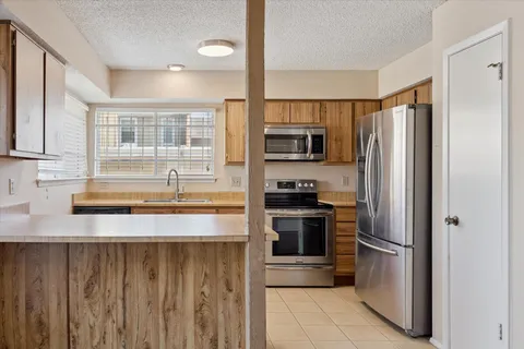 a kitchen with granite countertop a refrigerator stove and sink