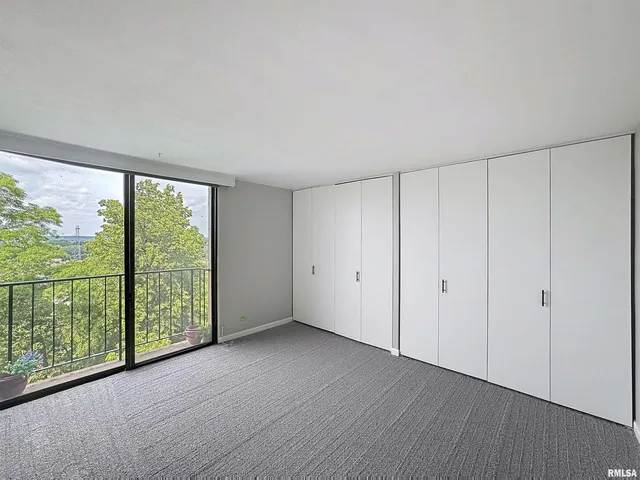 a view of an empty room with wooden floor and windows