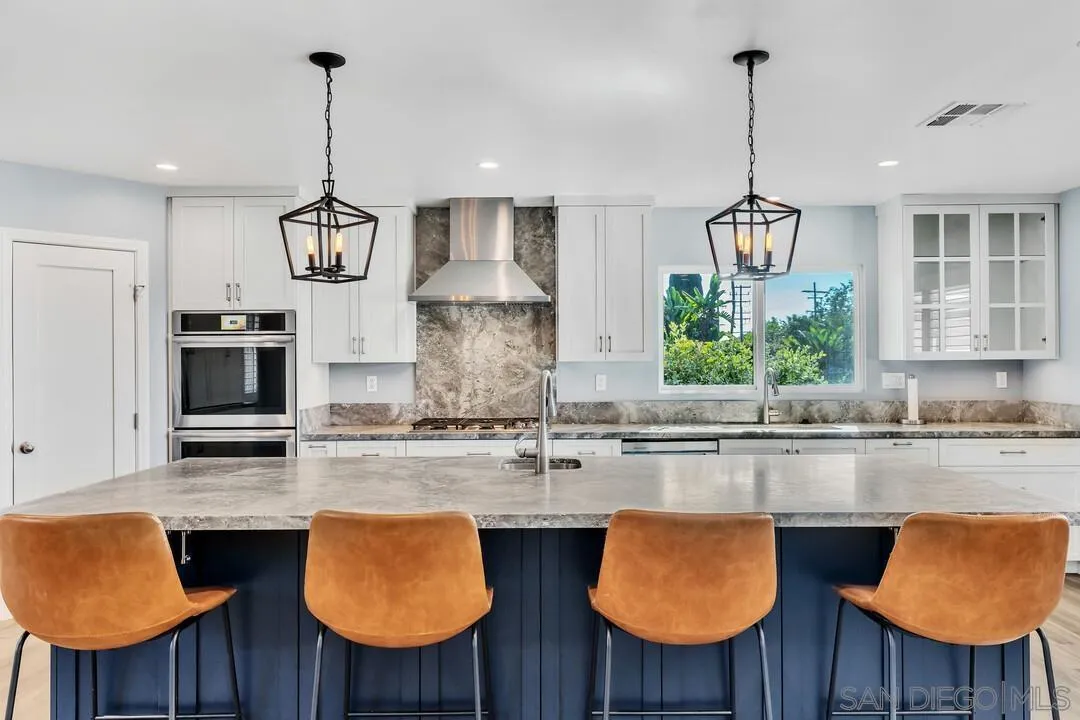 a kitchen with stainless steel appliances granite countertop a table chairs and a wooden floor