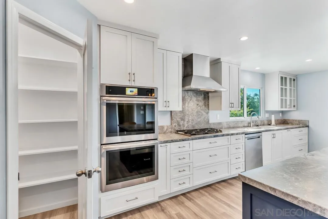 4502 Milton Street San Diego, CA 92110 - Photo 9 of 51 a kitchen with granite countertop white cabinets stainless steel appliances and a sink