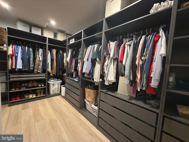 a view of walk in closet with clothes and shoes
