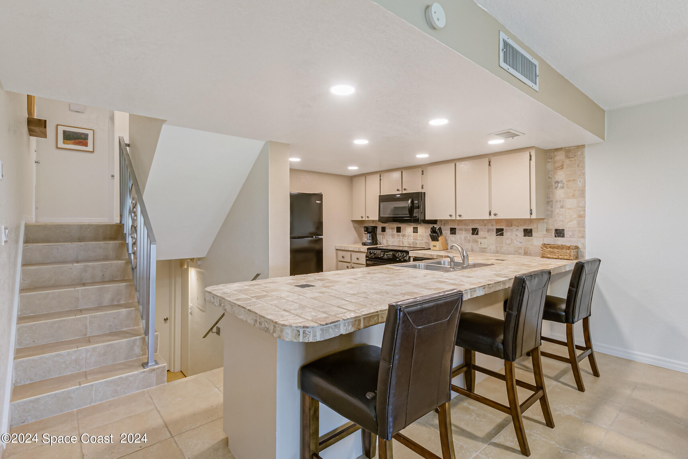 5050 Ocean Beach Boulevard Cocoa Beach, FL 32931 - Photo 16 of 33 a kitchen with stainless steel appliances granite countertop a table chairs sink and cabinets