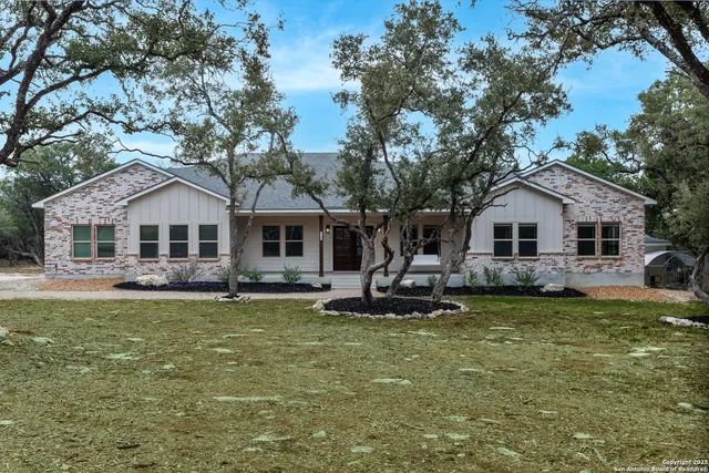 a front view of a house with a garden and trees