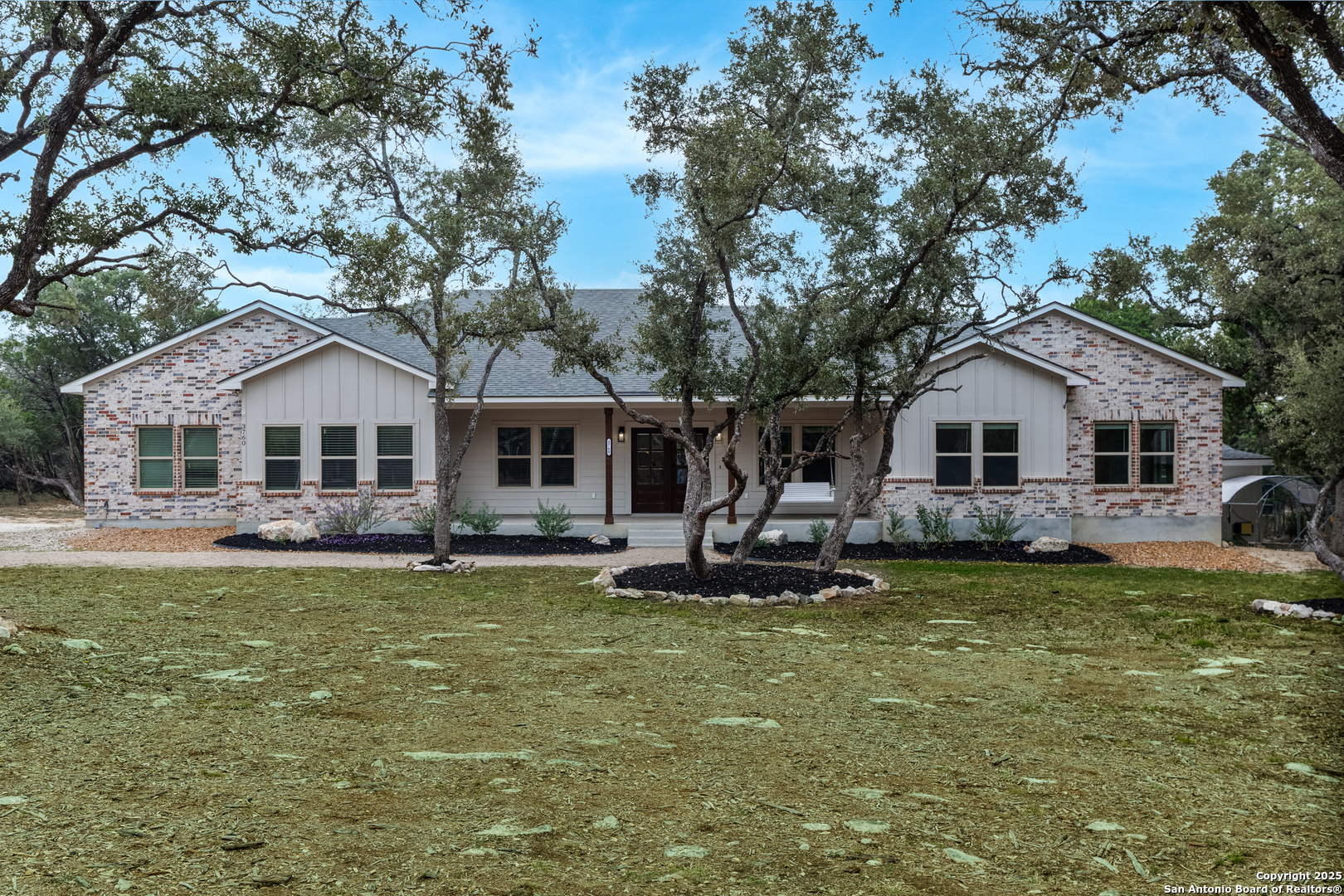 a front view of a house with a garden and trees