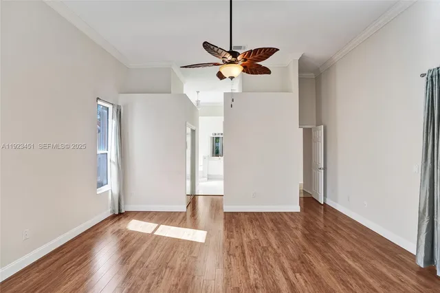 a view of empty room with wooden floor and ceiling fan