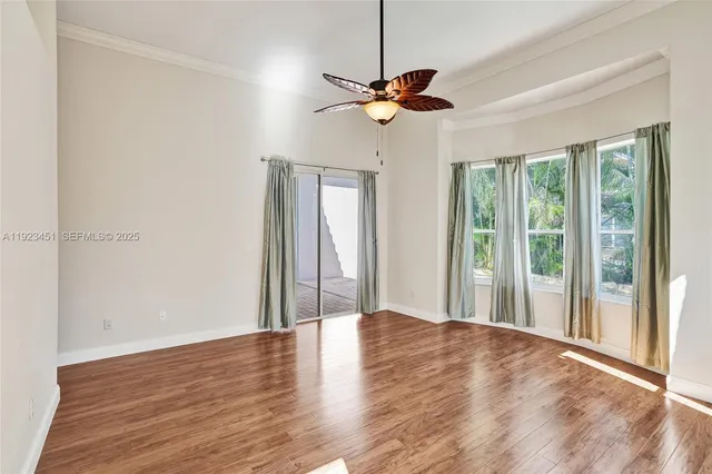 a view of empty room with wooden floor and fan