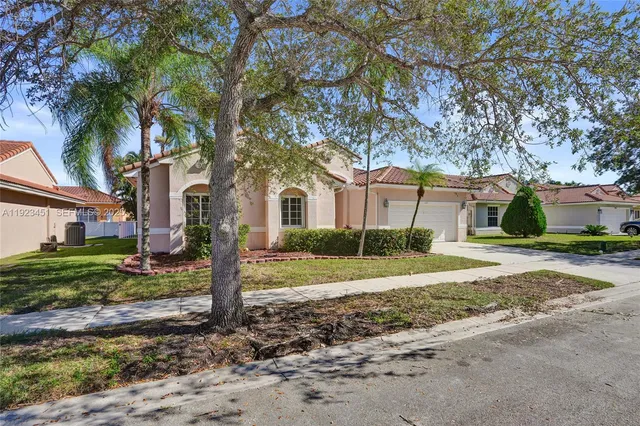 a view of a house with a yard and large tree