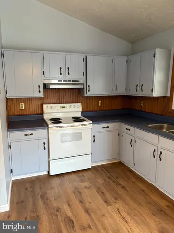 a view of a kitchen with a sink a refrigerator and white cabinets