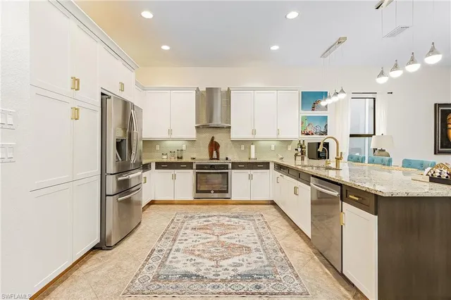 a kitchen with stainless steel appliances granite countertop a refrigerator sink and white cabinets