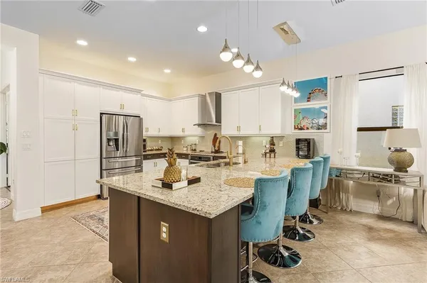 a large kitchen with kitchen island a dining table chairs and a refrigerator
