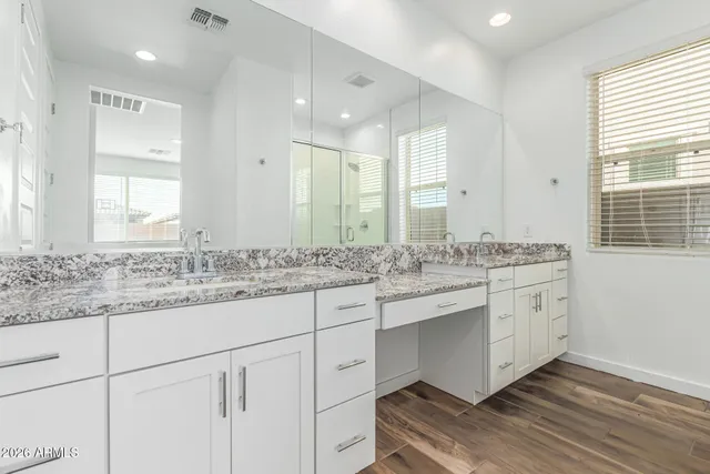 a bathroom with a granite countertop sink toilet mirror and shower