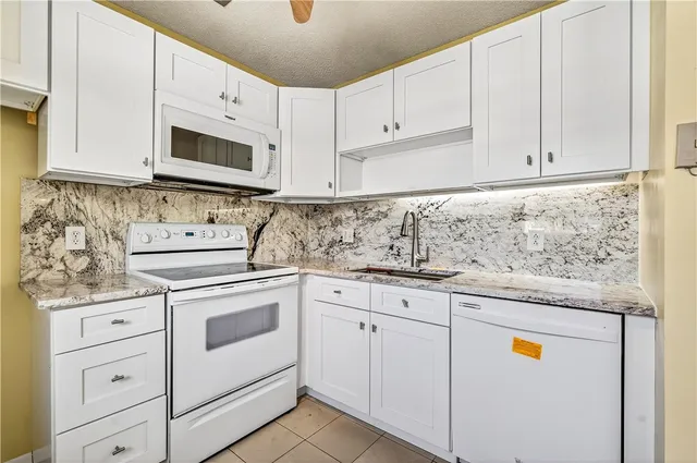 a kitchen with granite countertop white cabinets and white appliances