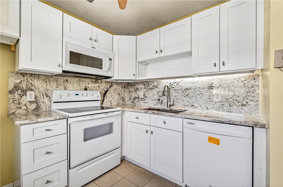 45 Vista Gdns Trail, Unit 202 Vero Beach, FL 32962 - Photo 1 of 32 a kitchen with granite countertop white cabinets and white appliances