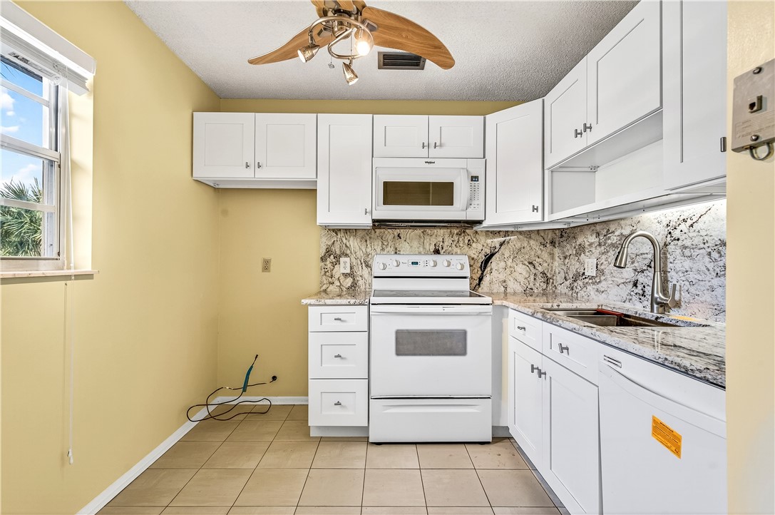 45 Vista Gdns Trail, Unit 202 Vero Beach, FL 32962 - Photo 7 of 32 a kitchen with stainless steel appliances a stove sink and cabinets