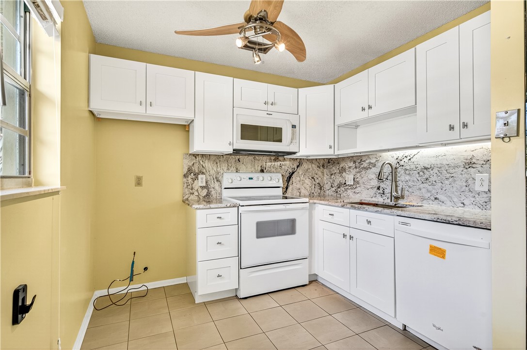 45 Vista Gdns Trail, Unit 202 Vero Beach, FL 32962 - Photo 8 of 32 a kitchen with granite countertop cabinets stainless steel appliances and a sink