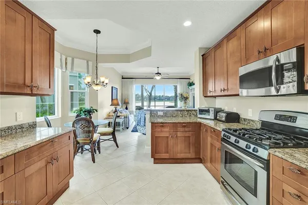 a kitchen with stainless steel appliances granite countertop a stove top oven a sink dishwasher a dining table and chairs with wooden floor