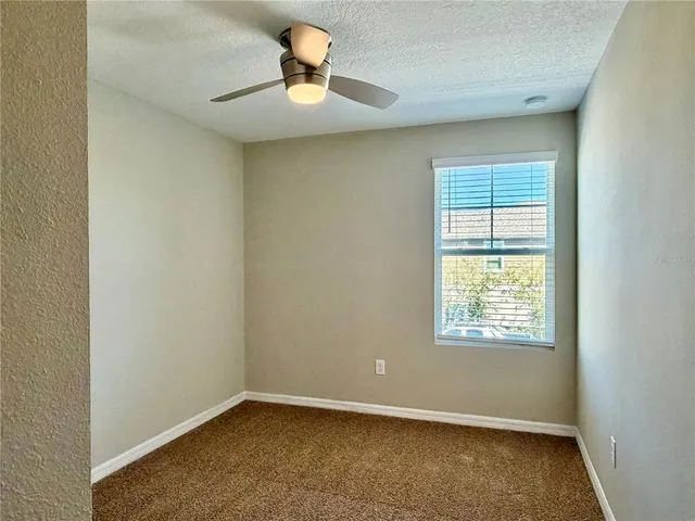 an empty room with windows and ceiling fan