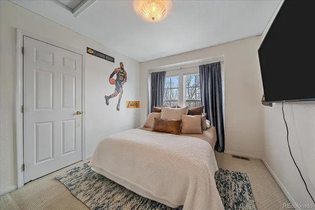 a bedroom with a bed and a flat tv screen on the dresser