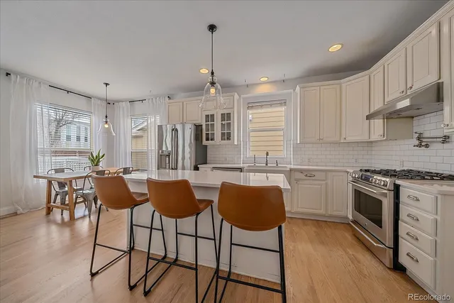 a kitchen with stainless steel appliances granite countertop a stove top oven a sink dishwasher a dining table and chairs with wooden floor