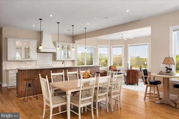 a kitchen with stainless steel appliances granite countertop a stove a sink a island with a dining table chairs and wooden cabinets