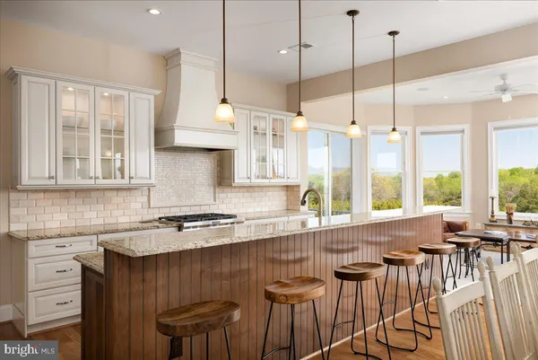 a kitchen with stainless steel appliances granite countertop a stove a sink dishwasher a refrigerator and white cabinets with wooden floor
