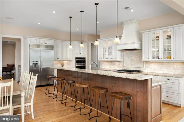 a open kitchen with stainless steel appliances granite countertop a stove top oven a sink a dining table and chairs with wooden floor