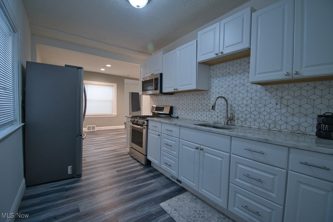 5402 Biddulph Road Cleveland, OH 44144 - Photo 3 of 20 Kitchen with appliances with stainless steel finishes, dark hardwood / wood-style flooring, backsplash, sink, and white cabinetry