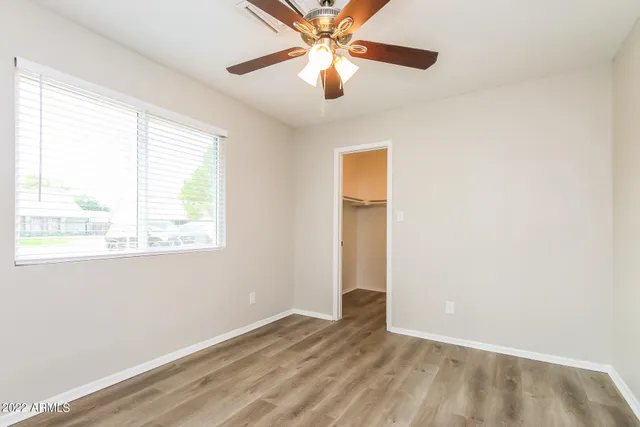 an empty room with a window and a fan