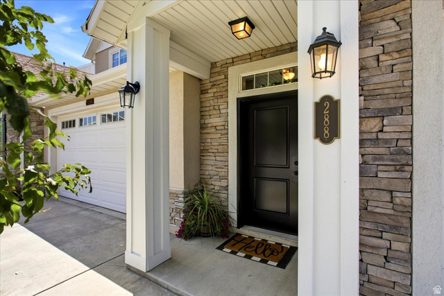 288 South 600 West Centerville, UT 84014 - Photo 2 of 27 Entryway featuring stone facade, a black panel door with transom window, and exterior lighting fixtures