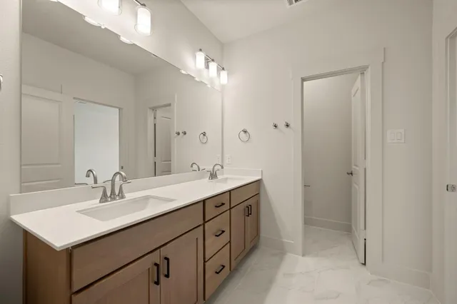 a view of a hallway with wooden floor and a bathroom