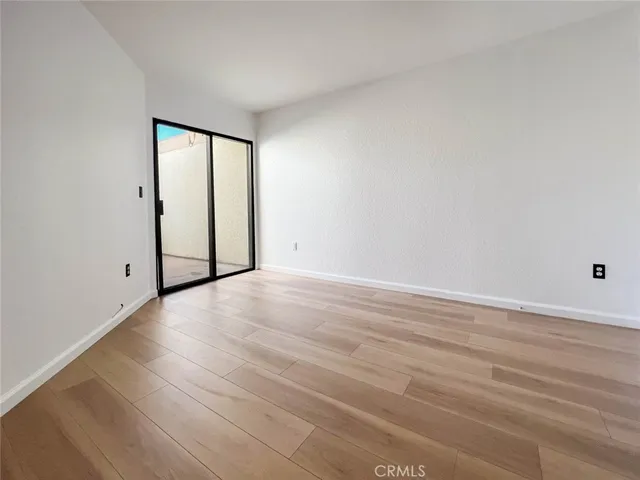 a view of an empty room with wooden floor and windows