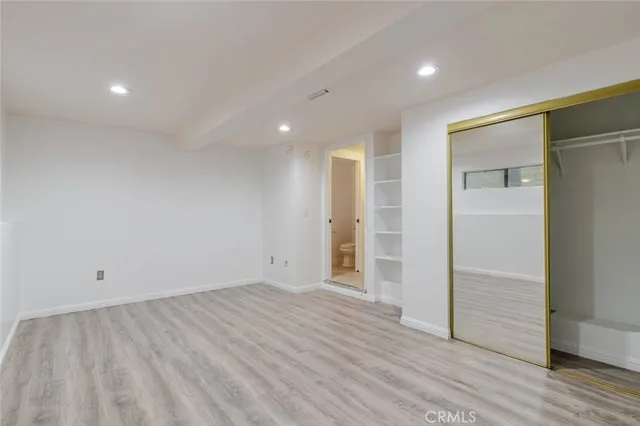 an empty room with wooden floor & closet area