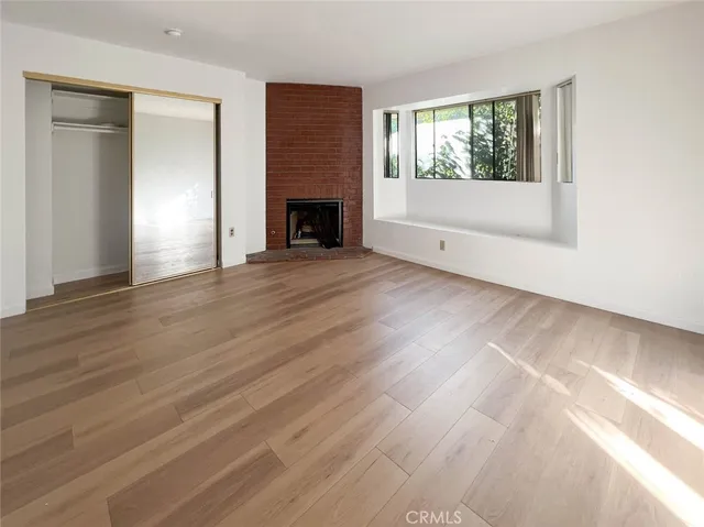 an empty room with wooden floor fireplace and windows