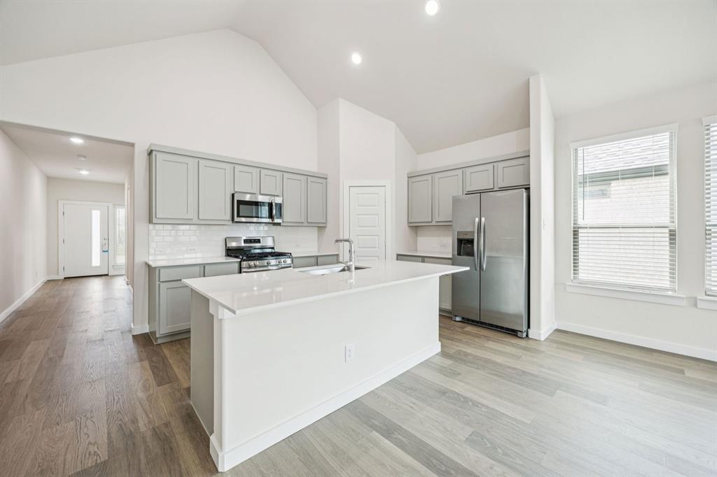 689 Moonlight Place Lavon, TX 75166 - Photo 6 of 29 a kitchen with stainless steel appliances a refrigerator stove a sink and a oven with wooden floor