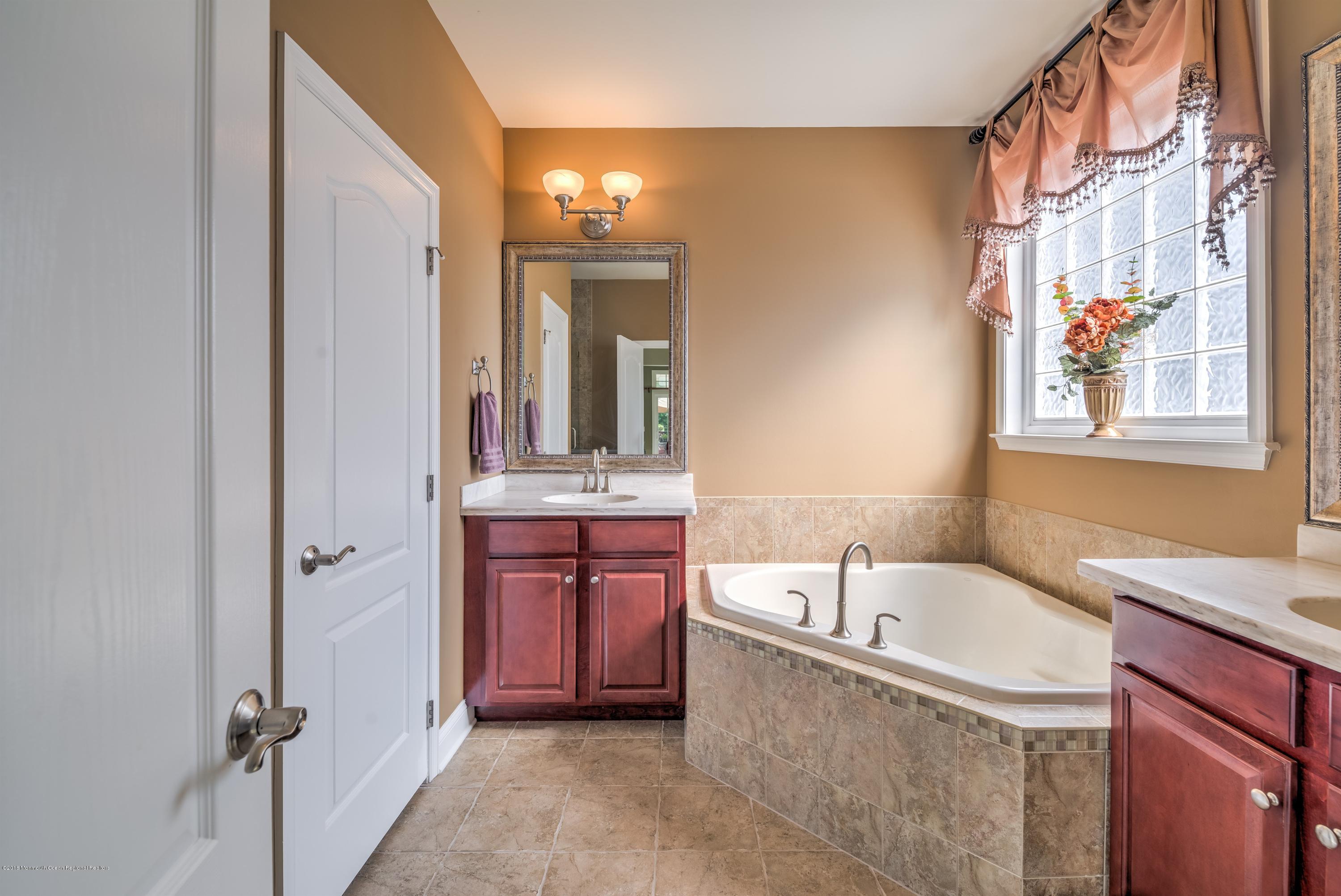 16 East Raphael Lane Farmingdale, NJ 07727 - Photo 19 of 50 a bathroom with a tub sink and mirror