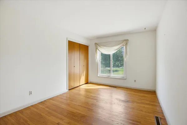 a view of an empty room with a window and wooden floor