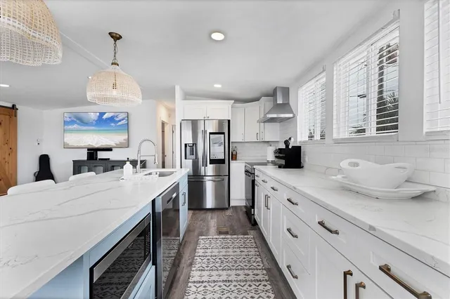 a large kitchen with stainless steel appliances kitchen island granite countertop a sink dishwasher a stove and a dining table with wooden floor