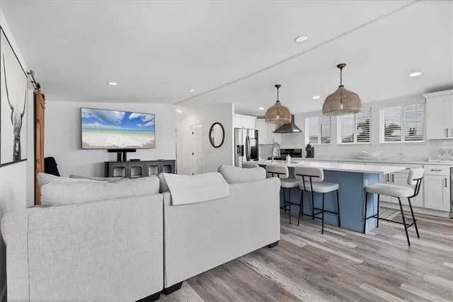 a living room with furniture kitchen view and a chandelier