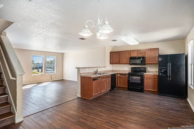 a large kitchen with a stove a sink dishwasher a refrigerator and a stove top oven with wooden floor