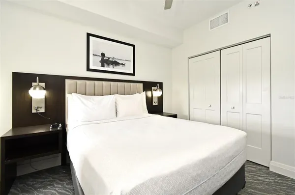 a bedroom with a large bed and a lamp on dresser