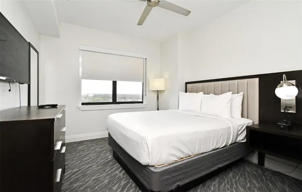 a large bed sitting in a bedroom next to a window and a flat tv screen on a dresser
