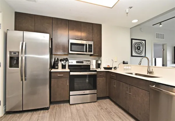 a kitchen with stainless steel appliances kitchen island granite countertop a refrigerator and a sink