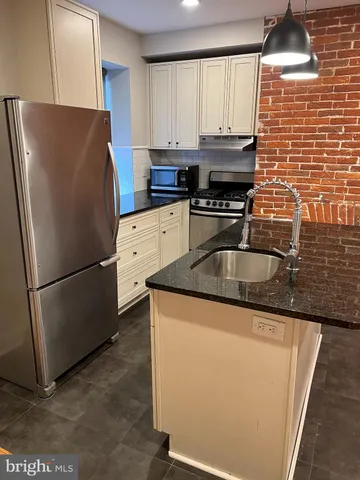 a kitchen with granite countertop a refrigerator and a stove top oven