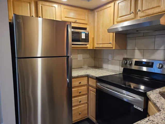 a kitchen with stainless steel appliances granite countertop a refrigerator a stove and a sink